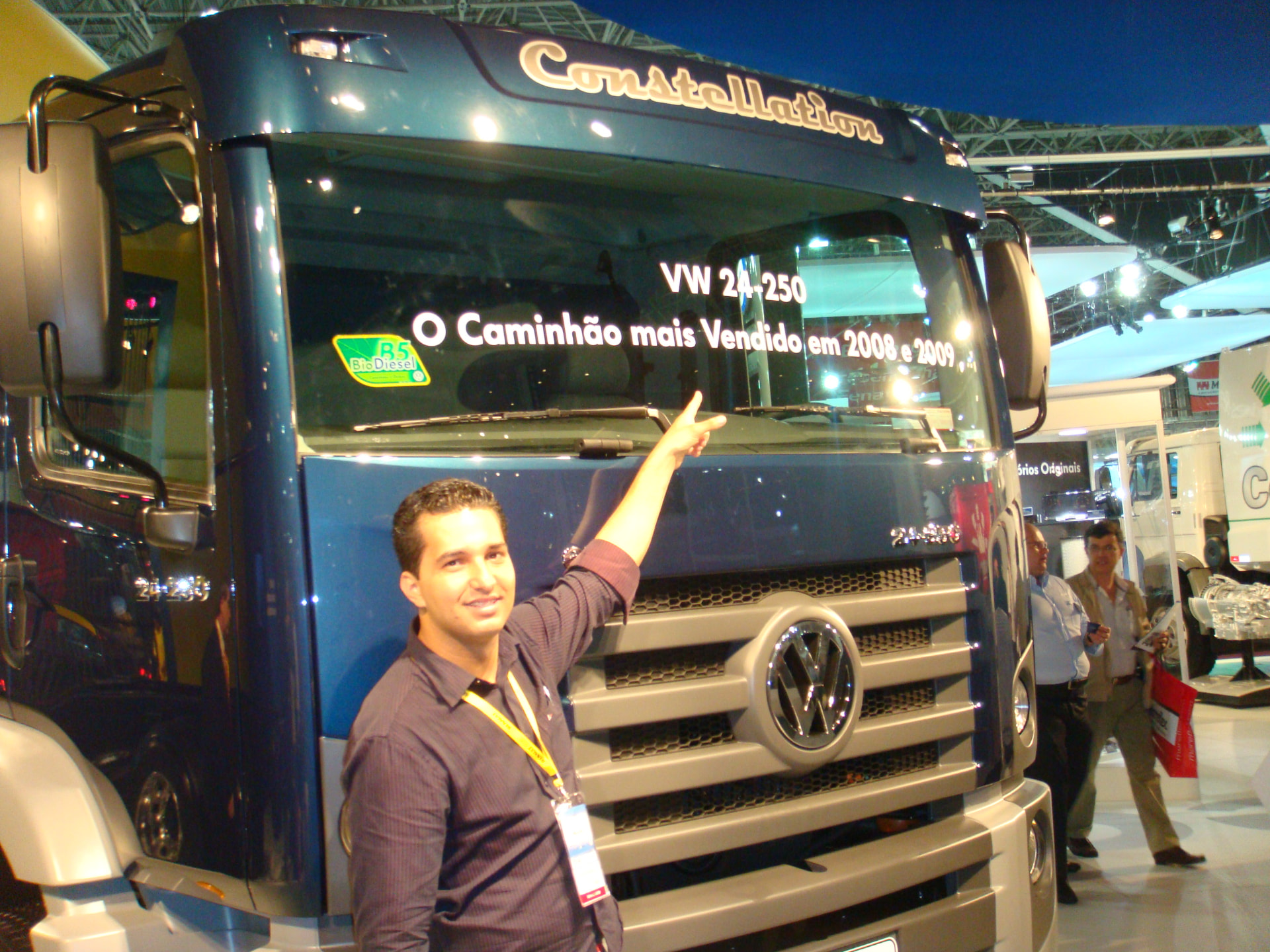 Jonathas apontando para o para-brisa de um caminhão Volkswagen Constellation