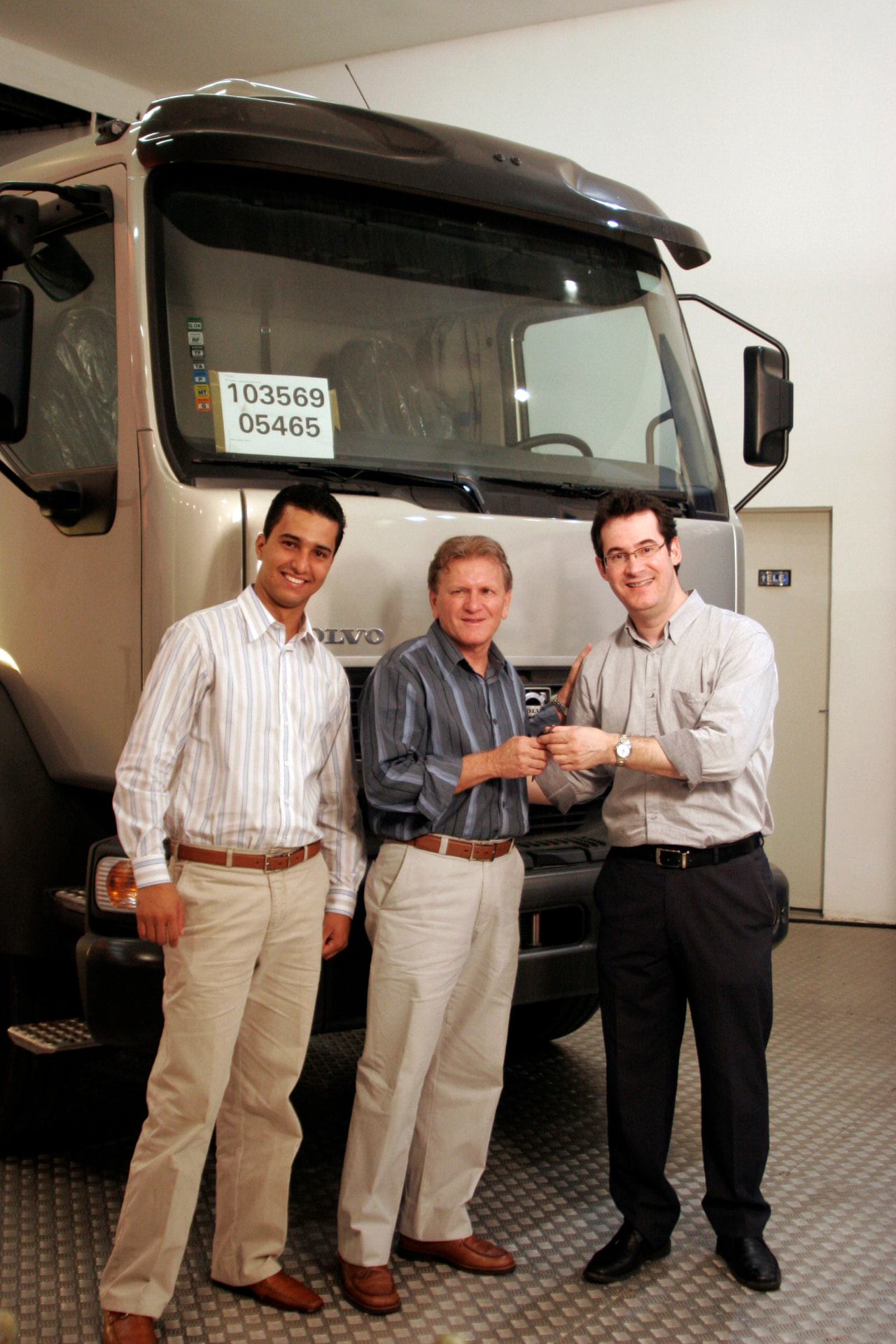 Jonathas com dois homens diante de um caminhão Volvo