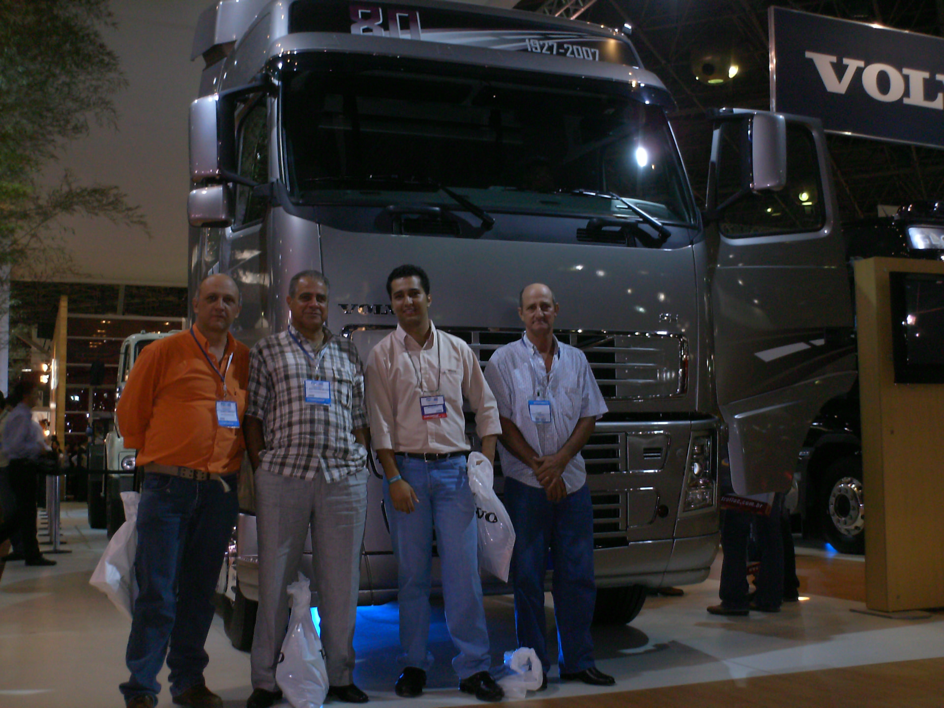 Jonathas com três homens em frente a um caminhão Volvo em feira